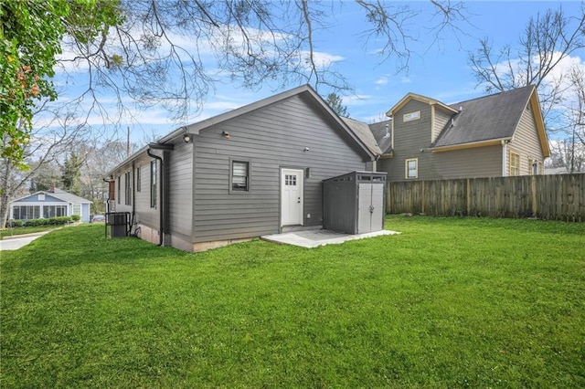 rear view of property with a yard, an outbuilding, and fence