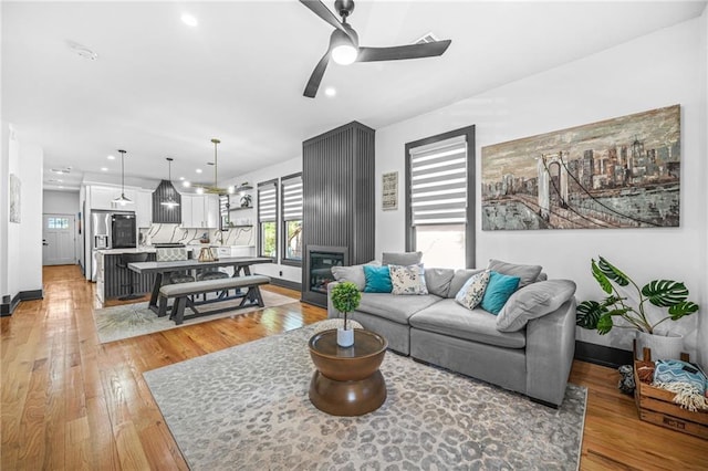 living area with recessed lighting, baseboards, light wood-style flooring, and a fireplace