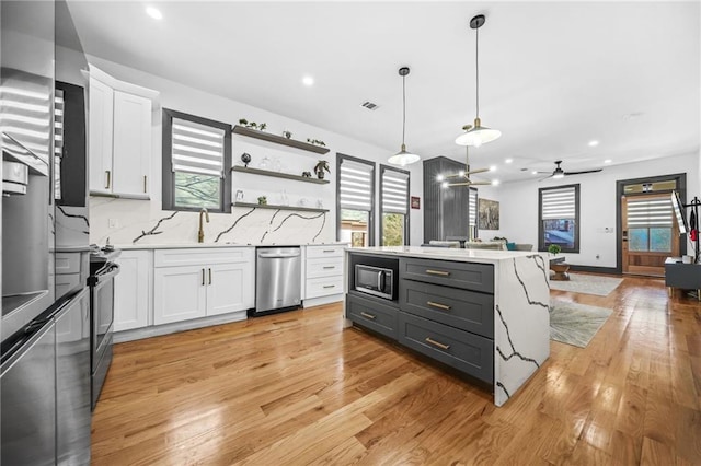 kitchen with built in microwave, hanging light fixtures, white cabinetry, and light wood-style floors