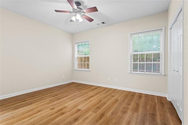 empty room with wood-type flooring, a wealth of natural light, and ceiling fan