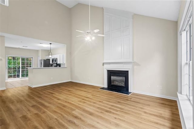 unfurnished living room with ceiling fan, light hardwood / wood-style flooring, and high vaulted ceiling