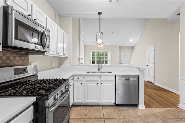 kitchen with white cabinets, kitchen peninsula, sink, and appliances with stainless steel finishes