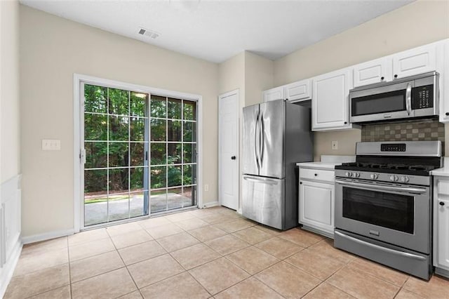 kitchen featuring white cabinets, backsplash, light tile patterned floors, and stainless steel appliances