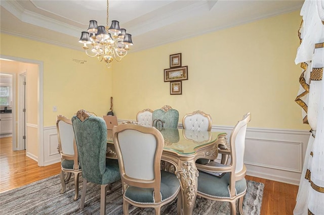 1644 Beaver Creek Ln, Snellville, GA 30078 - dining room featuring a chandelier, wood finished floors, ornamental molding, a wainscoted wall, and a raised ceiling