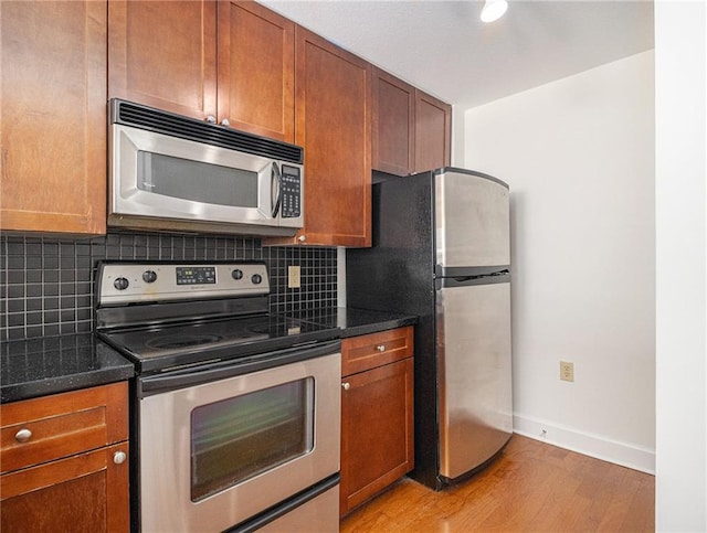 kitchen with tasteful backsplash, baseboards, light wood-type flooring, brown cabinetry, and stainless steel appliances