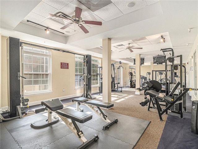 workout area featuring baseboards, a tray ceiling, and a ceiling fan