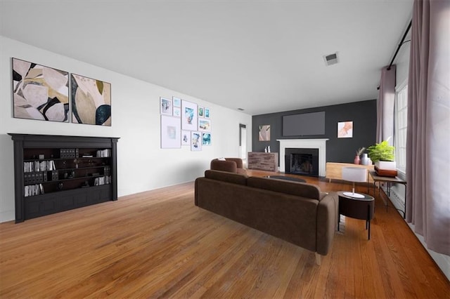 living area with a fireplace, wood finished floors, and visible vents