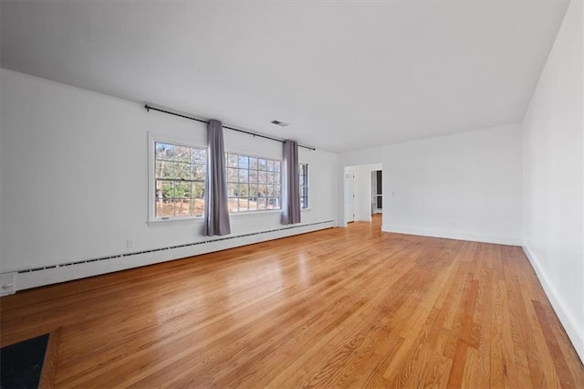 interior space featuring a baseboard heating unit, light wood-type flooring, and baseboards