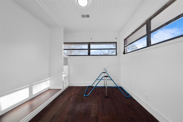 unfurnished room featuring a healthy amount of sunlight, visible vents, baseboards, and wood finished floors