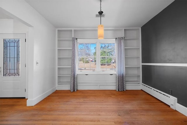 doorway to outside featuring visible vents, built in features, baseboards, wood finished floors, and a baseboard heating unit