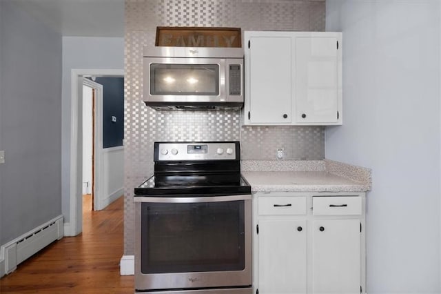 kitchen with a baseboard radiator, light countertops, backsplash, appliances with stainless steel finishes, and white cabinetry