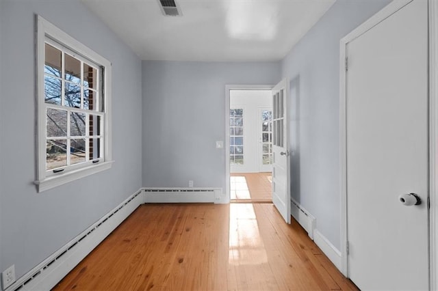 interior space featuring a baseboard heating unit, visible vents, and light wood-style floors