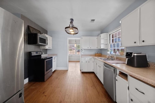 kitchen with visible vents, white cabinets, decorative light fixtures, stainless steel appliances, and light countertops