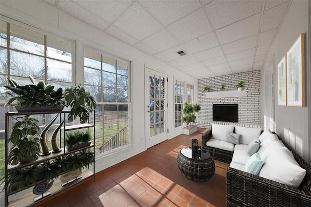 sunroom / solarium featuring a paneled ceiling, a fireplace, and visible vents