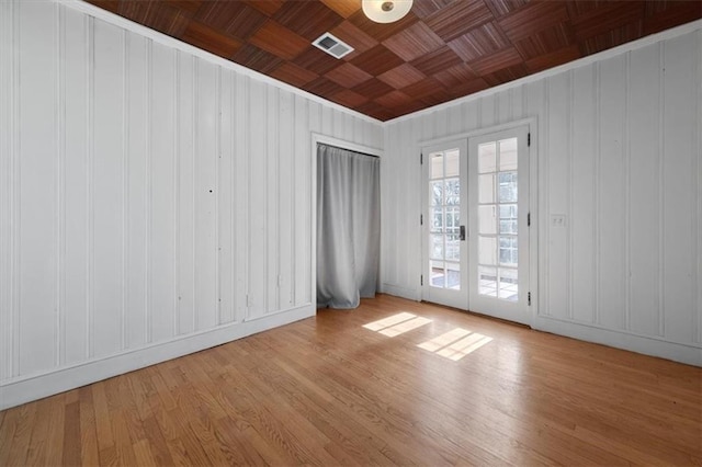 empty room with wooden ceiling, french doors, light wood-type flooring, and visible vents