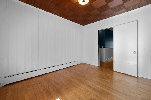 spare room with wood ceiling, a baseboard heating unit, and wood finished floors