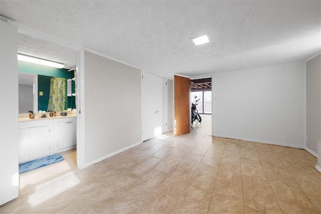 spare room featuring a textured ceiling and baseboards