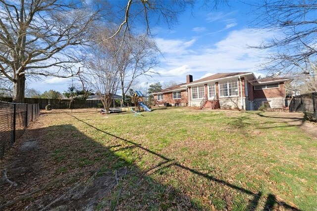 view of yard featuring entry steps, a playground, and a fenced backyard