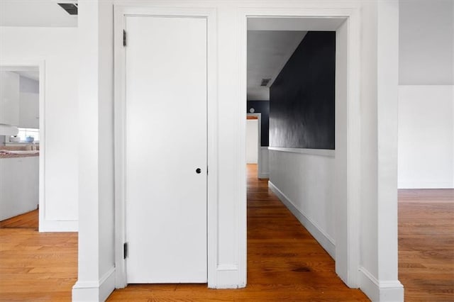 hall with visible vents and wood finished floors