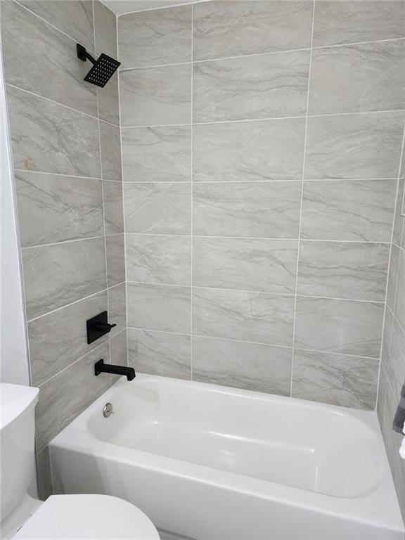 bathroom featuring toilet and tiled shower / bath