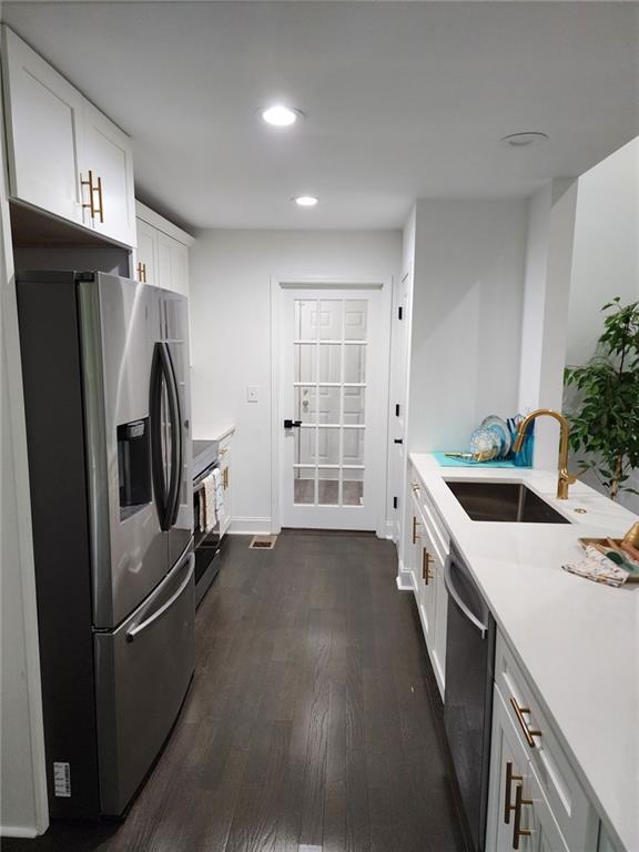 kitchen featuring dark wood-type flooring, sink, white cabinets, and stainless steel appliances