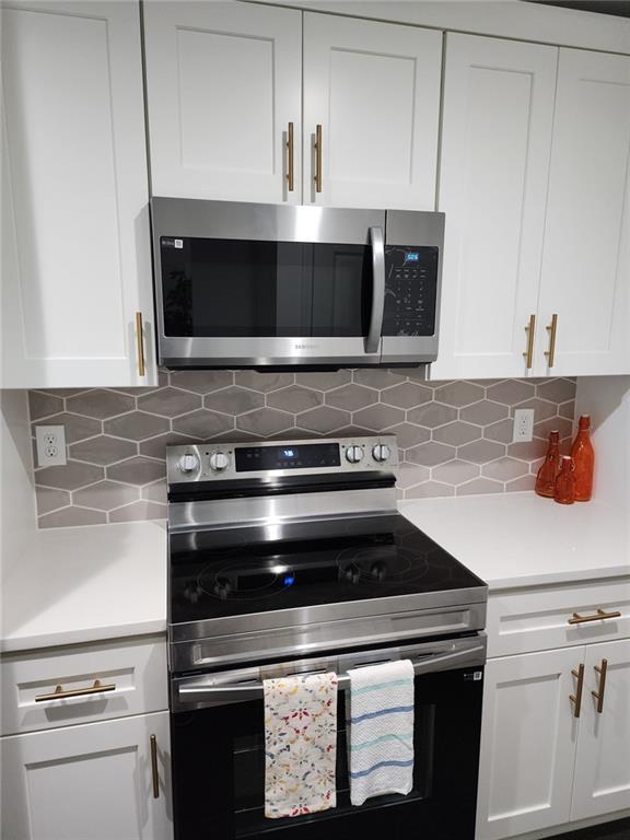 kitchen featuring stainless steel appliances, white cabinetry, and tasteful backsplash