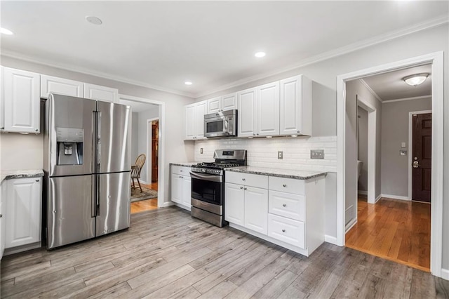 2941 Foothill Trl, Marietta, GA 30066 - kitchen featuring appliances with stainless steel finishes, light wood-style floors, white cabinetry, tasteful backsplash, and light stone countertops