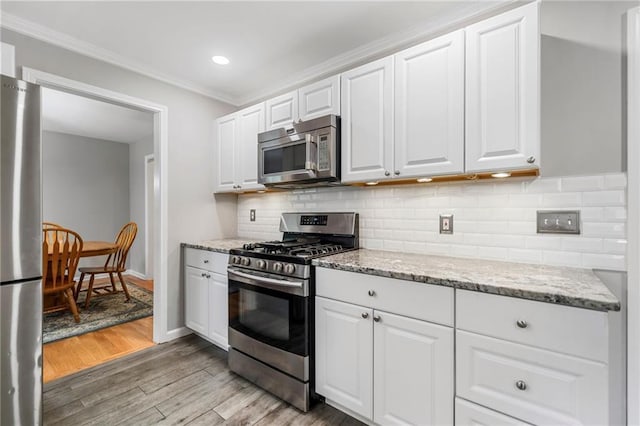 2941 Foothill Trl, Marietta, GA 30066 - kitchen with stainless steel appliances, light wood finished floors, white cabinets, crown molding, and light stone countertops