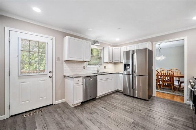 2941 Foothill Trl, Marietta, GA 30066 - kitchen featuring appliances with stainless steel finishes, ornamental molding, white cabinetry, light wood finished floors, and decorative backsplash