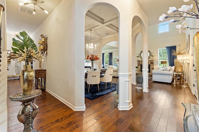 entrance foyer with beamed ceiling, a chandelier, coffered ceiling, dark hardwood / wood-style floors, and a high ceiling