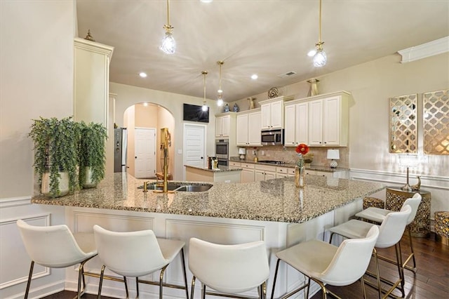 kitchen featuring kitchen peninsula, dark hardwood / wood-style floors, pendant lighting, and stainless steel appliances