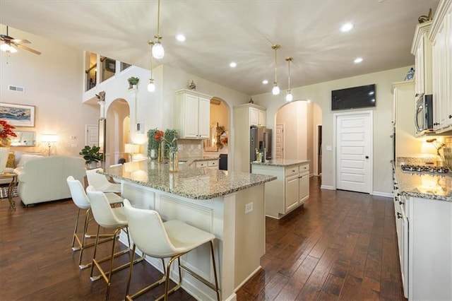 kitchen featuring pendant lighting, kitchen peninsula, stainless steel appliances, light stone countertops, and ceiling fan