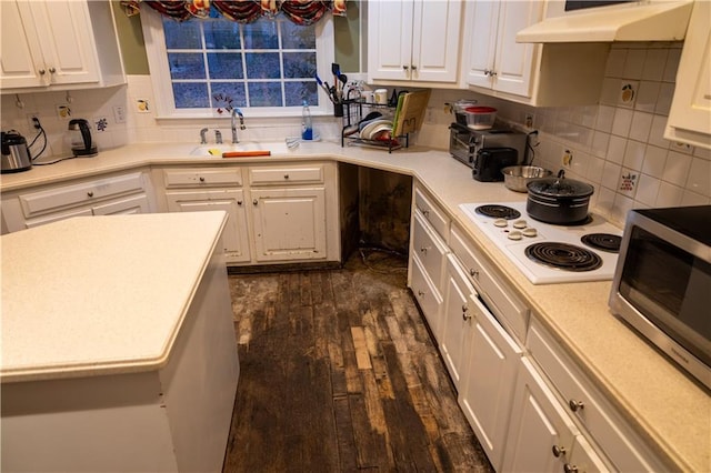 kitchen with white electric cooktop, stainless steel microwave, under cabinet range hood, white cabinetry, and a sink