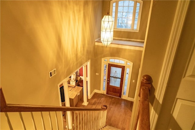 foyer with a high ceiling, wood finished floors, visible vents, and baseboards