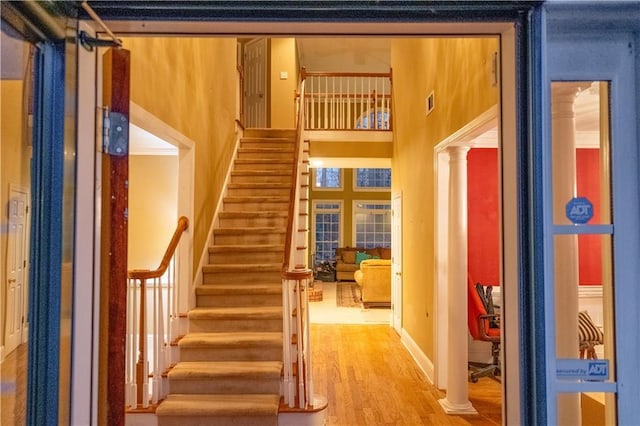 interior space with decorative columns, a towering ceiling, and wood finished floors