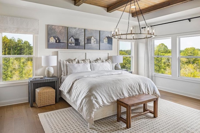 bedroom featuring a chandelier, baseboards, wood finished floors, multiple windows, and wood ceiling