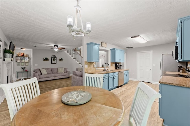 1338 Jefferson Station Rd, Jefferson, GA 30549 - dining space with light wood-type flooring, a textured ceiling, ceiling fan with notable chandelier, and stairway