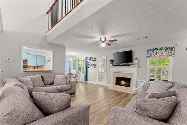 1338 Jefferson Station Rd, Jefferson, GA 30549 - living room featuring visible vents, ceiling fan with notable chandelier, wood finished floors, and a wealth of natural light