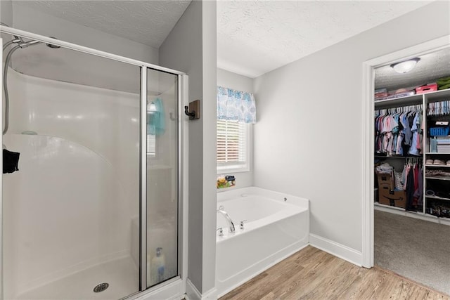 1338 Jefferson Station Rd, Jefferson, GA 30549 - full bathroom with a garden tub, wood finished floors, a textured ceiling, a spacious closet, and a stall shower