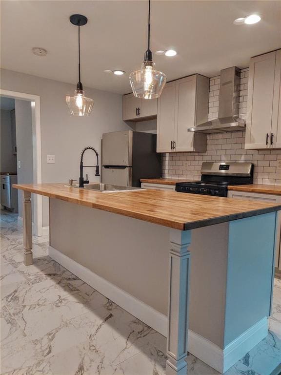 kitchen with wall chimney exhaust hood, stainless steel gas stove, butcher block counters, and fridge