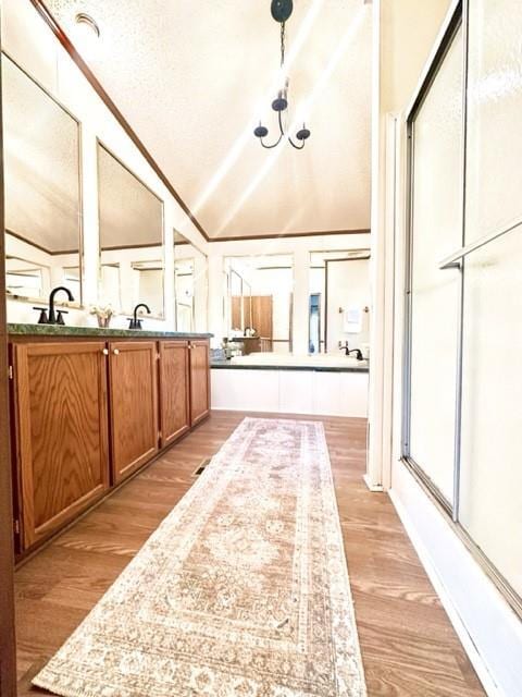 bathroom featuring lofted ceiling, double vanity, wood finished floors, and a shower with shower door