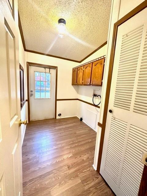 laundry room featuring washer hookup, crown molding, cabinet space, a textured ceiling, and wood finished floors