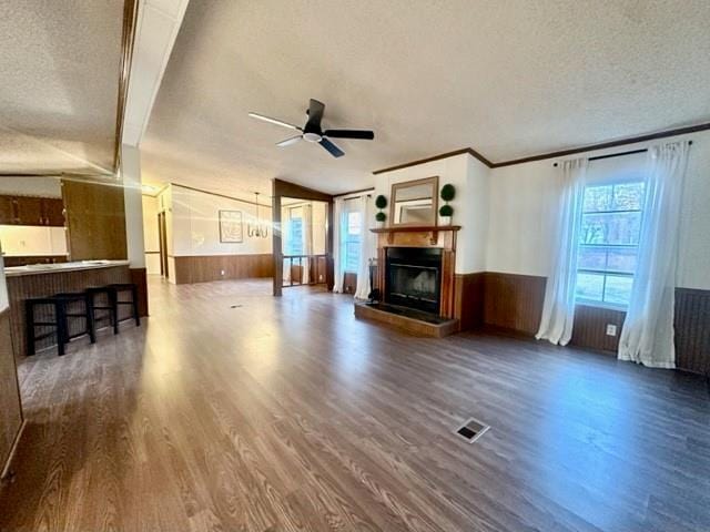 unfurnished living room with wainscoting, visible vents, and a textured ceiling