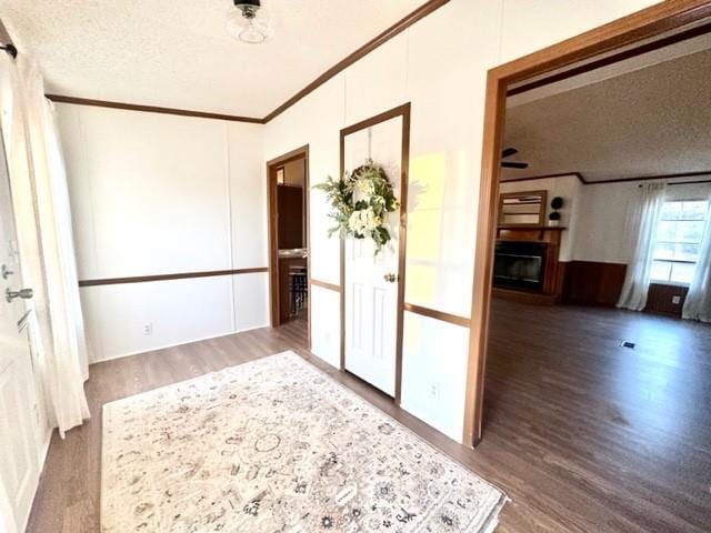 interior space featuring a textured ceiling, ornamental molding, and wood finished floors