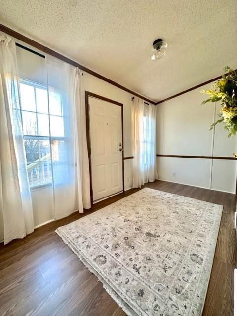 entryway with a textured ceiling, ornamental molding, and dark wood-style flooring