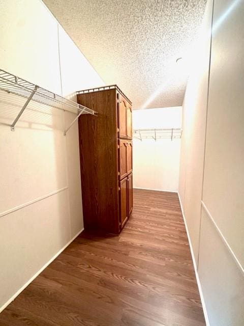 hallway with a textured ceiling and wood finished floors