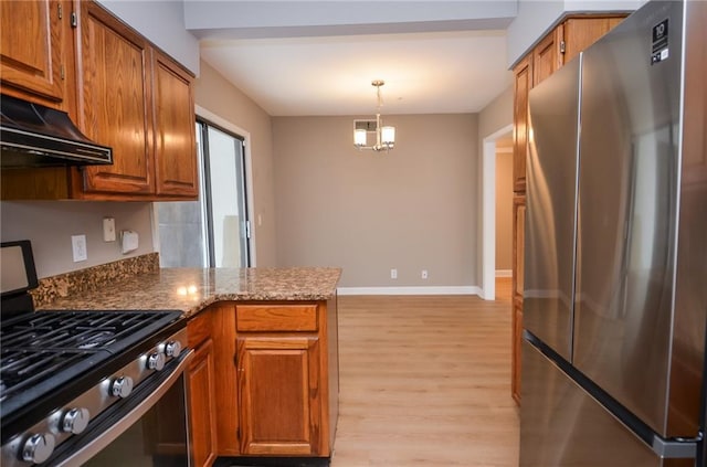 kitchen featuring appliances with stainless steel finishes, brown cabinets, a peninsula, an inviting chandelier, and light wood-style floors