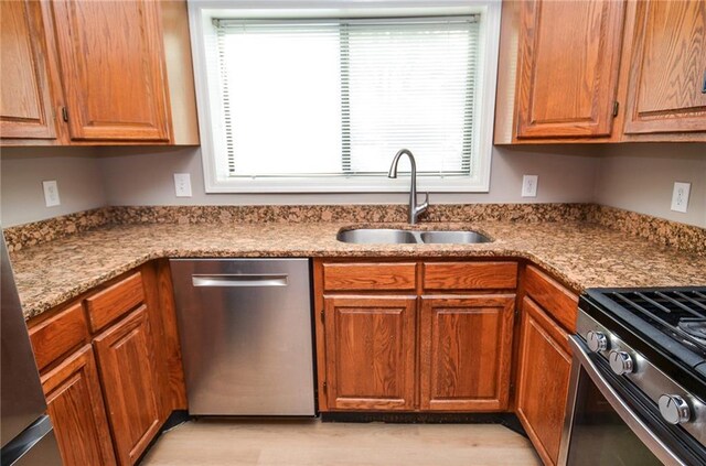 kitchen featuring appliances with stainless steel finishes, brown cabinets, and a sink