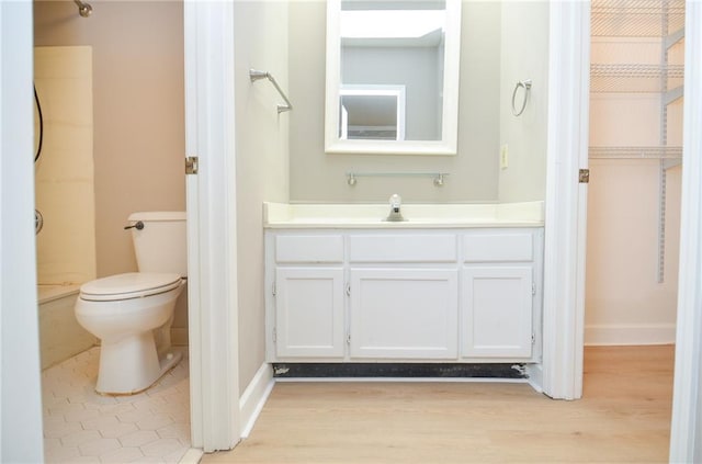 bathroom with toilet, baseboards, wood finished floors, and vanity