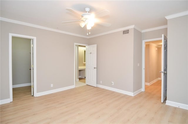 unfurnished bedroom with a walk in closet, crown molding, visible vents, light wood-style floors, and baseboards